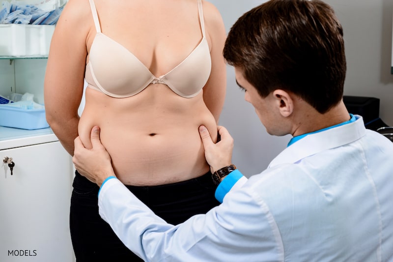 A woman during her consultation determining how much excess skin to remove.